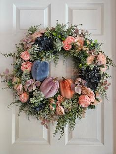 a wreath with flowers and succulents hanging on a door