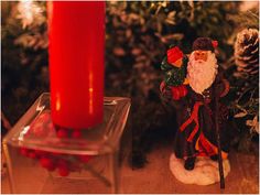 a christmas decoration with a candle and santa clause figurine