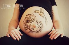 a pregnant woman's belly with flowers painted on it and the words blooming lotus henna written in cursive writing