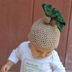 a small child wearing a crocheted hat with a green bow