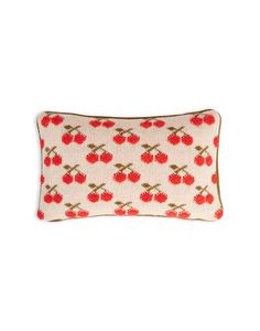 a red and white pillow with cherries on the front, against a white background