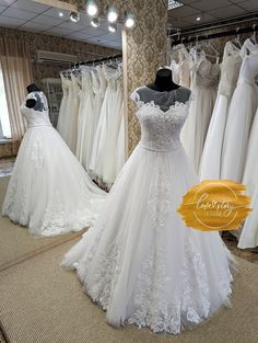 wedding dresses are on display in a bridal shop, with the price tag below them