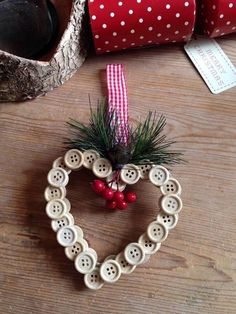 a heart shaped ornament with buttons and pine branches in the shape of a heart