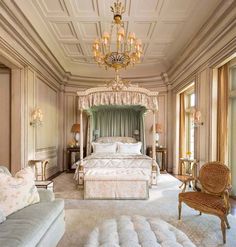 a bedroom with a large bed, chandelier and two couches in it