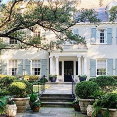 a large white house with blue shutters on the front door and steps leading up to it