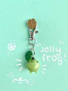 a keychain with a green frog charm hanging from it's side on a blue background