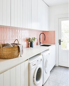 a white kitchen with pink tiles on the backsplash, and a washing machine