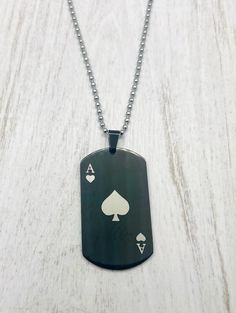 a black dog tag with white playing cards on it is sitting on a table next to a chain