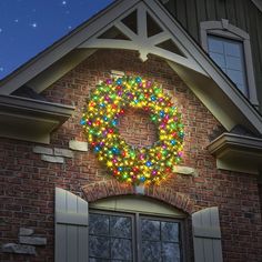 a lighted wreath on the side of a brick building