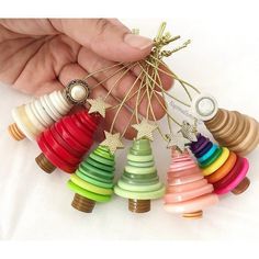 a person holding a bunch of colorful wooden christmas tree ornaments in their hand with the string attached to them