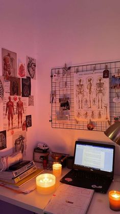 a laptop computer sitting on top of a desk next to a lit candle and pictures