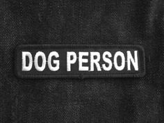 a dog person patch on the back of a blue jacket with white writing that reads,'dog person '