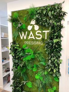 a green wall with plants growing on it and the words wast pressing written in white