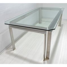 a glass table with metal legs on a white floor