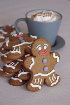 several gingerbread cookies with white icing next to a cup of coffee on a table