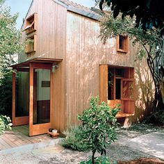 a small wooden house surrounded by trees and plants