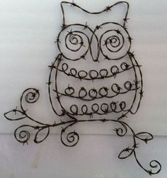 an iron wire owl sitting on top of a white wall with barbed wire around it's eyes