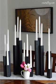 black and white candles are arranged on a table with a pink flower in the middle