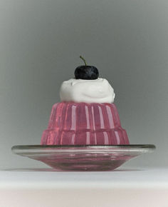 a small cake sitting on top of a glass plate covered in whipped cream and a black berry