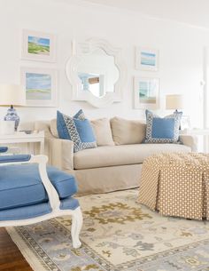 a living room with white furniture and blue pillows on the couches in front of a mirror