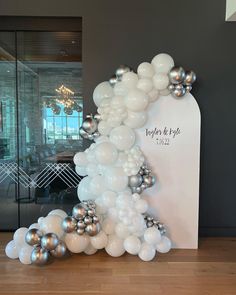 balloons are arranged in the shape of an arch with silver and white balls on it