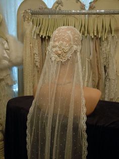 a mannequin wearing a veil in front of some dresses