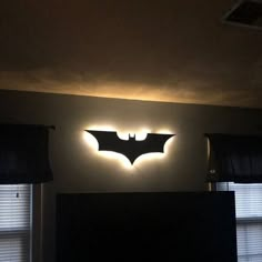 the batman logo is lit up on the wall above the bed in this dark room