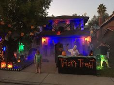 two children standing in front of a house decorated for trick'n'treat at night