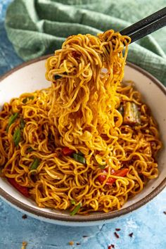 a bowl of noodles with chopsticks in it on a blue and white table cloth