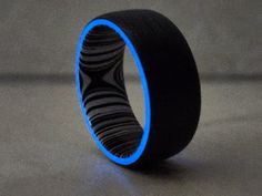 a black and blue ring sitting on top of a gray table next to a wall