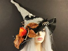 "The Bat and Bone Witch Hat is crocheted and then felted, creating the classic shape. A touch of elegance with a lace bat flying from the dark foliage with the full moon above. The black gauze hat band has a skeleton hand and long bones, with one dangling off the side. An orange rose blooms from the leaves and twigs. Soft but still firm enough to hang on a hook or rest on your table. Felting makes this hat naturally water repellent. This hat is tall and if desired, can be stuffed with paper at t Witchy Brimmed Costume Hats For Parties, Curved Brim Hat For Halloween Themed Events, Halloween Wide Brim Fitted Mini Hat, Themed Costume Accessories With Curved Brim, Themed Costume Accessories With Curved Brim For Costume Party, Fitted Wide Brim Mini Hat For Halloween, Witchy Hats For Halloween Costume Party, Witchy Costume Hats And Headpieces For Party, Halloween Fitted Wide Brim Costume Hat