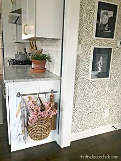 a kitchen with pictures on the wall and flowers in a basket next to an oven