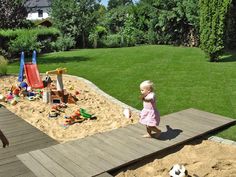 two young children playing in the sand at a play yard with toys and building blocks