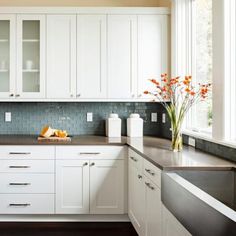 a kitchen filled with lots of white cabinets and counter top space next to a window