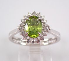 an oval cut peridot and diamond ring on a clear surface with white background