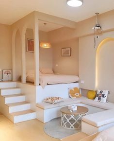 a living room filled with white furniture and lots of stairs leading up to the top floor