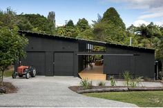 a tractor is parked in front of a black building with an open door on the side