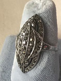 "Gorgeous original antique Art Deco ring in sterling silver with marcasites set in a geometric design. The shape is wonderful. This ring looks fabulous in.. it is an elongated three dimensional dome in a modified marquise shape with geometric detailing. Full of sparkling marcasites which were all the rage with flappers in the Deco era. Marcasite jewels, sometimes known as \"black diamonds\" were the poor girls answer to diamonds but in a lot of ways are more endearing and fascinating, as the Old Art Deco Silver Oval Rings, Silver Oval Art Deco Rings, Antique Silver Diamond Ring Collectible, Silver Oval Diamond Ring Collectible, Silver Oval Diamond Ring For Collectors, Vintage Oval Marcasite Rings, Victorian Style Silver Oval Diamond Ring, Victorian Style Oval Silver Diamond Ring, Vintage Marcasite Oval Rings