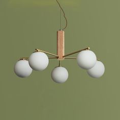 a chandelier with five white balls hanging from it's brass frame and four light bulbs