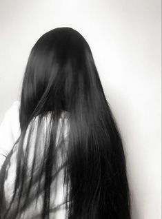 black and white photograph of woman's back with long hair blowing in the wind