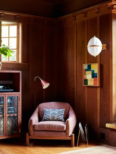 a living room with wood paneling and a chair in front of a television on a stand