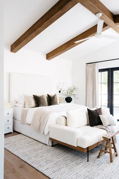 a large white bed sitting inside of a bedroom next to a wooden ceiling mounted flat screen tv