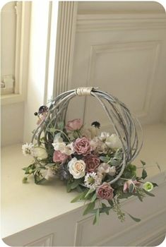 a flower arrangement sitting on top of a white counter next to a window sill