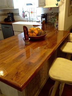 a bowl of oranges sitting on top of a kitchen counter next to two stools