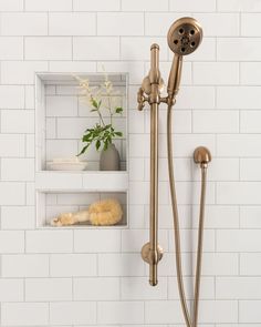 a shower head and hand shower in a white tiled bathroom with shelves on the wall