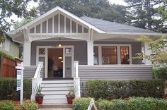 a gray house with white trim on the front door and steps leading up to it