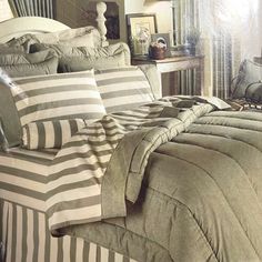 a bed with striped comforter and pillows on top of it in front of a window