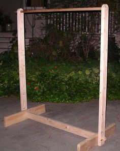 a wooden frame sitting on top of cement next to bushes and flowers in the background