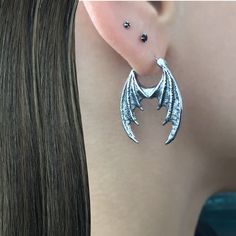 Dragon Wings hoop earrings  are made of 316 Stainless steel and have oxidation, to add more depth and details. Hoops are perfect for both men and women. Total height: 30 mm Total width: 23 mm Gauge: 22G (regular piercing) Listin for 1 pair (2 earrings) *RETURNS / REFUNDS * -If you would like to return you purchase , please contact us within 7 days of receiving your package and we will accept the return.Return will only be made to the product, and not the shipping cost.  -Buyer is  responsible for the return shipping costs . -All jewelry must be returned unworn and in their original condition . *LOST MAIL* Once the package is marked as DELIVERED by the post office, we are not responsible for misplaced or stolen packages. *MAIL THEFT* If parcel is stoled or vandalized, please contact USPS ma Gothic Horned Jewelry For Halloween, Gothic Horned Metal Jewelry, Horned Gothic Metal Jewelry, Gothic Hoop Cartilage Earrings, Gothic Internally Threaded Hoop Cartilage Earrings, Gothic Metal Hoop Earrings, Gothic Metal Jewelry With Dragon Design, Gothic Silver Metal Piercings, Alternative Silver Jewelry For Pierced Ears