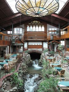 the inside of a building with tables and chairs next to a river running through it